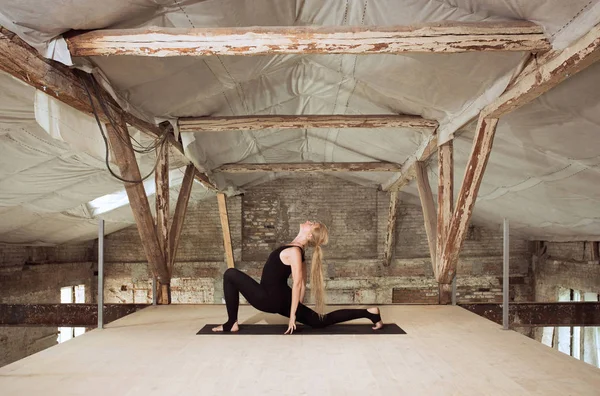 Terk edilmiş bir şantiyede genç kadın yoga egzersizleri — Stok fotoğraf