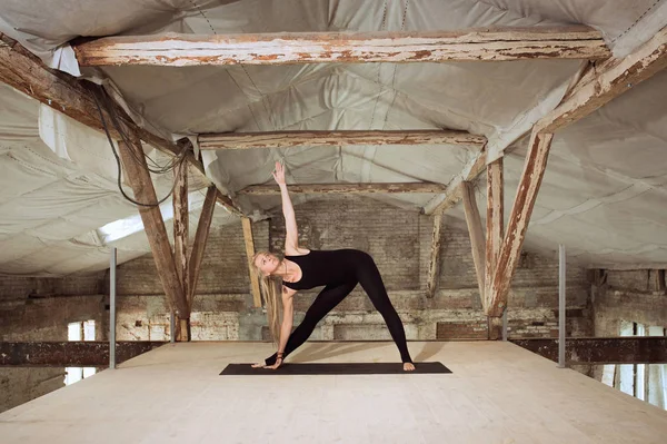 Giovane donna esercita yoga in un cantiere abbandonato — Foto Stock