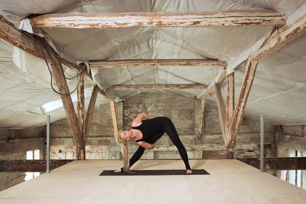 Giovane donna esercita yoga in un cantiere abbandonato — Foto Stock