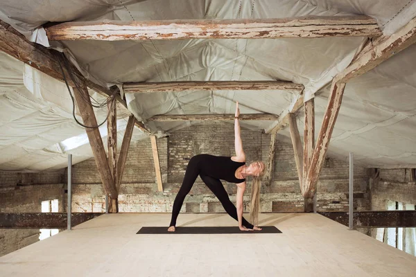 Giovane donna esercita yoga in un cantiere abbandonato — Foto Stock