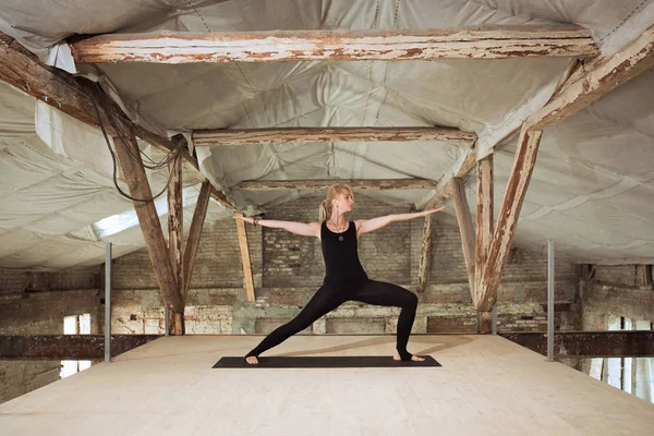 Young woman exercises yoga on an abandoned construction site