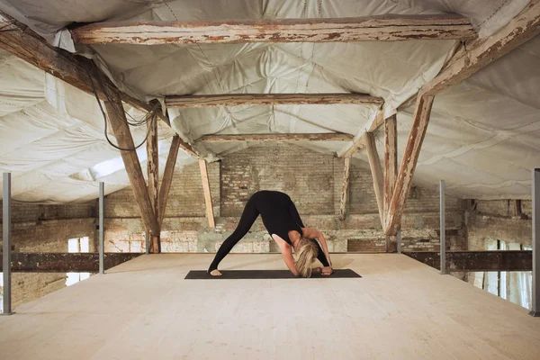 Giovane donna esercita yoga in un cantiere abbandonato — Foto Stock