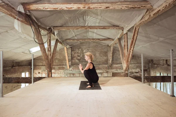 Young woman exercises yoga on an abandoned construction site