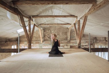 Terk edilmiş bir şantiyede genç kadın yoga egzersizleri