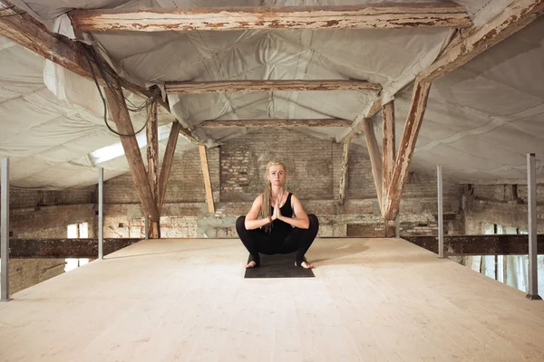 Young woman exercises yoga on an abandoned construction site — Stock Photo, Image