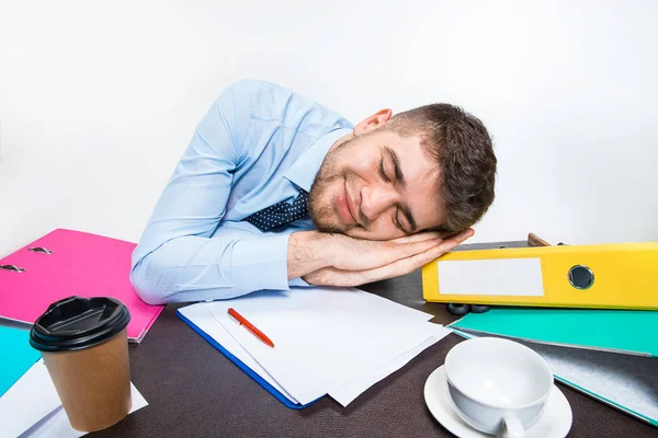 Le jeune homme dort effrontément sur le bureau pendant ses heures de travail — Photo