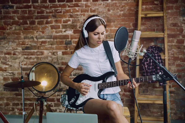 Mulher gravando música, tocando guitarra e cantando em casa — Fotografia de Stock