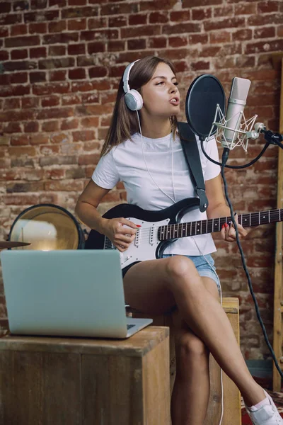 Vrouw muziek opnemen, gitaar spelen en zingen thuis — Stockfoto