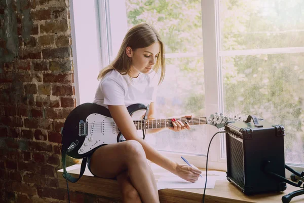 Mulher gravando música, tocando guitarra e cantando em casa — Fotografia de Stock