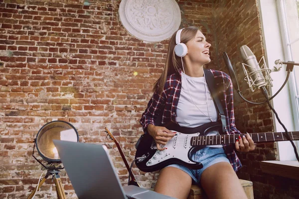 Mulher gravando música, tocando guitarra e cantando em casa — Fotografia de Stock