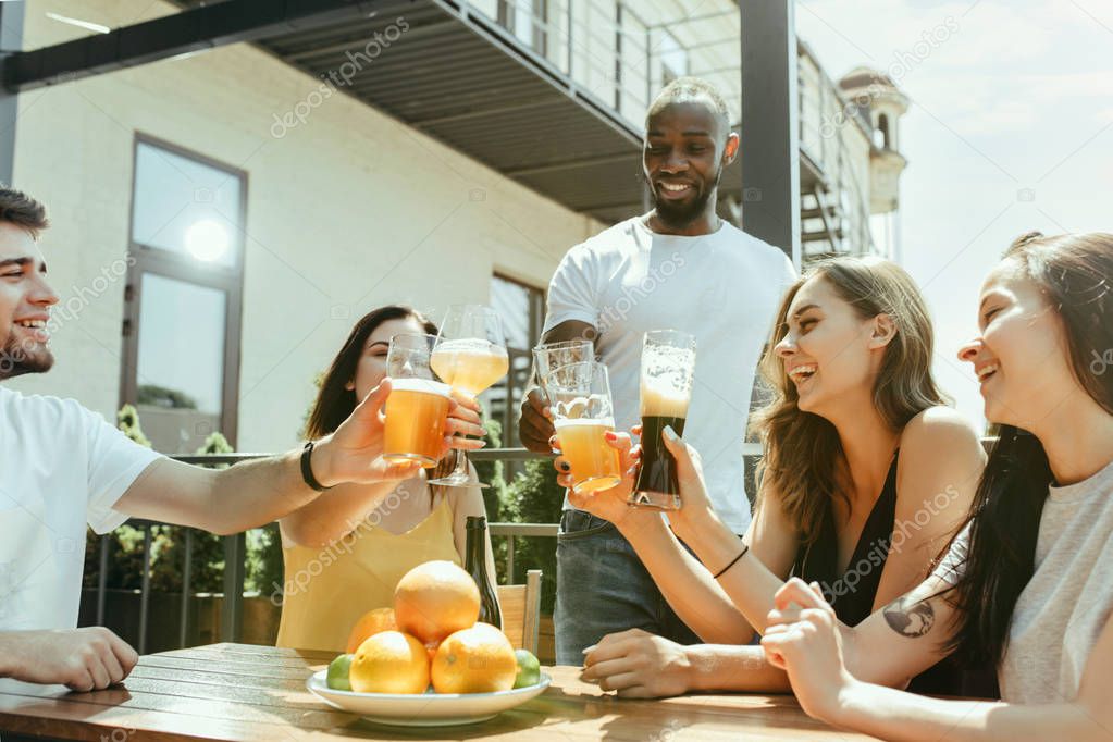 Young group of friends drinking beer and celebrating together