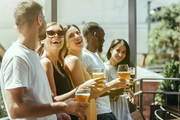 Young group of friends drinking beer and celebrating together