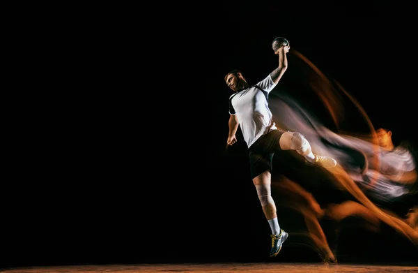 Young handball player against dark studio background in mixed light — Stock Photo, Image
