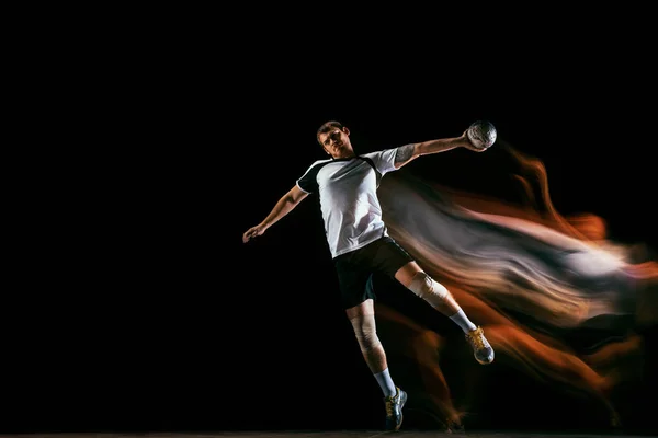 Młody gracz piłki ręcznej przeciwko ciemnym tle studyjnej w mieszanym świetle — Zdjęcie stockowe