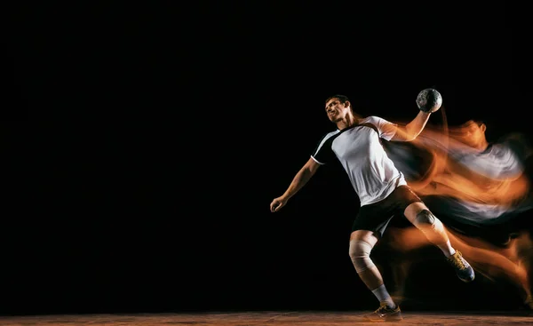 Young handball player against dark studio background in mixed light Stock Photo