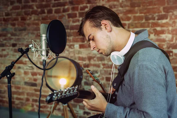 Junger Mann nimmt Musik auf, spielt Gitarre und singt zu Hause — Stockfoto