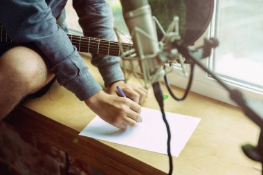 Genç adam müzik kayıt, gitar çalmak ve evde şarkı söylemek
