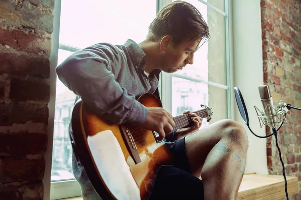 Jonge man muziek opnemen, gitaar spelen en zingen thuis — Stockfoto