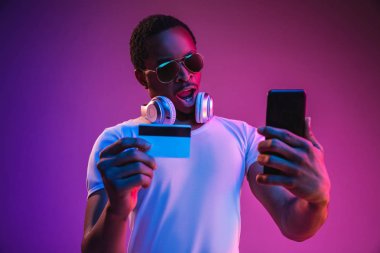 Neon ışıkta müzik dinleyen genç Afrikalı-Amerikan Mans