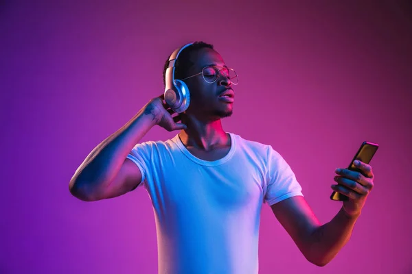 Jovens homens afro-americanos ouvindo música em luz de néon — Fotografia de Stock