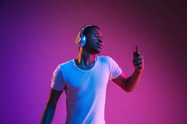 年轻的非洲裔美国男子在霓虹灯下听音乐 — 图库照片