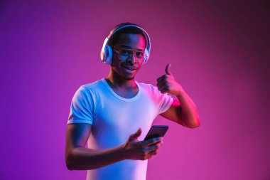Neon ışıkta müzik dinleyen genç Afrikalı-Amerikan Mans