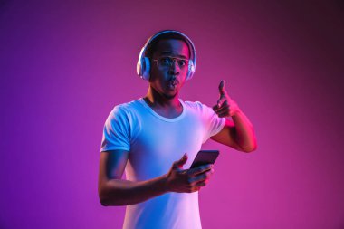 Neon ışıkta müzik dinleyen genç Afrikalı-Amerikan Mans