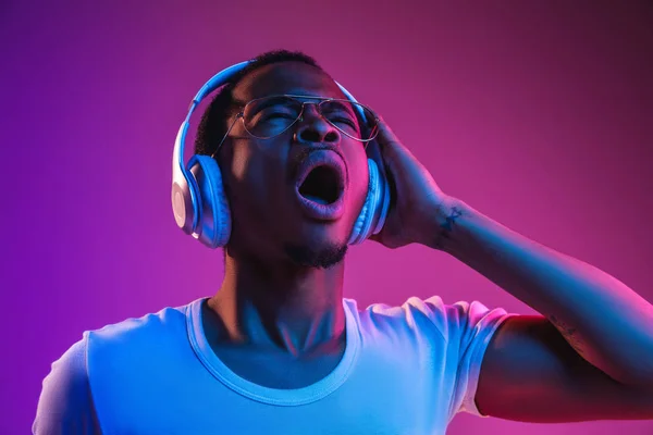 Молодий афроамериканський чоловік слухає музику в неоновому світлі — стокове фото