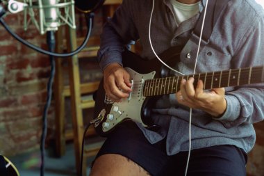 Genç adam müzik kayıt, gitar çalmak ve evde şarkı söylemek