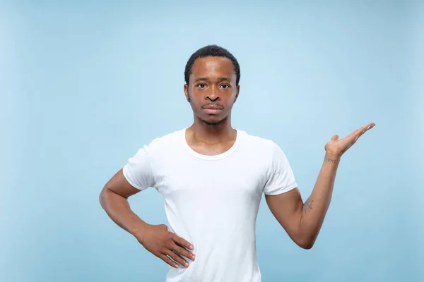 Half-length close up portrait of young man on blue background.