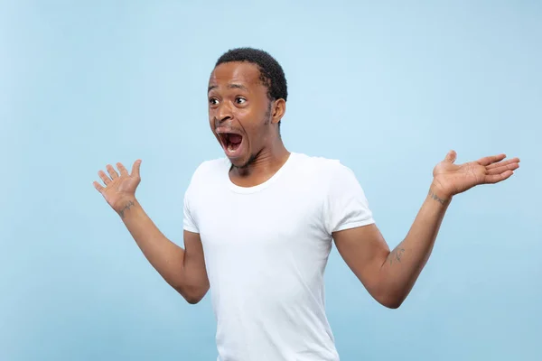 Halblanges Nahaufnahme-Porträt eines jungen Mannes auf blauem Hintergrund. — Stockfoto