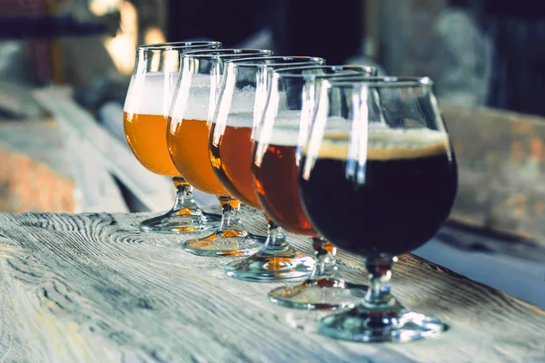 Vasos de diferentes tipos de cerveza sobre fondo de madera —  Fotos de Stock