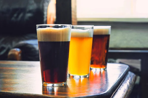 Szklanki różnego rodzaju piwa na drewnianym tle — Zdjęcie stockowe