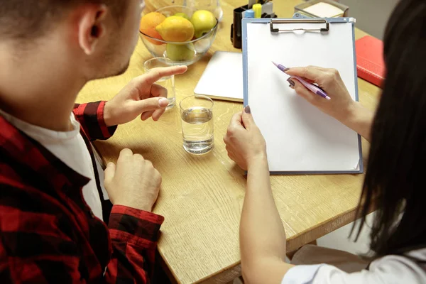 Smiling nutritionist showing a healthy diet plan to patient — Stock Photo, Image