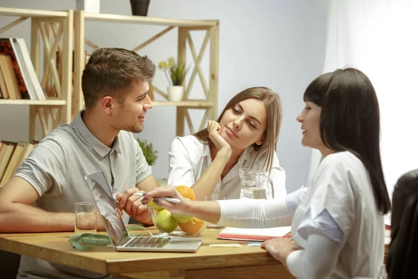 Nutrizionista sorridente che mostra un piano di dieta sana al paziente — Foto Stock