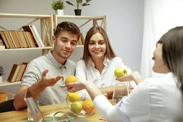 Nutrizionista sorridente che mostra un piano di dieta sana al paziente — Foto Stock