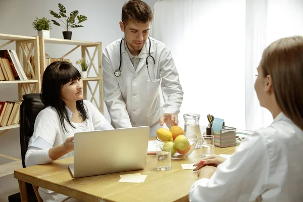 Nutricionistas sonrientes mostrando un plan de dieta saludable para el paciente —  Fotos de Stock