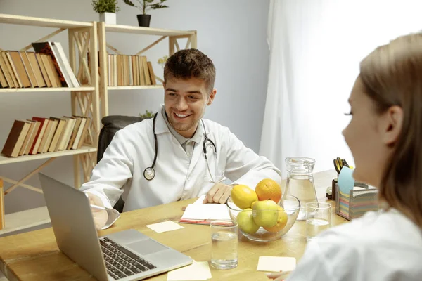 Nutricionista sonriente mostrando un plan de dieta saludable para el paciente —  Fotos de Stock
