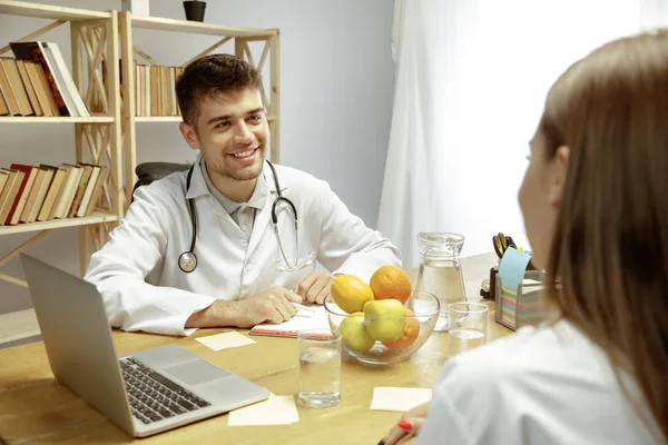 Nutricionista sonriente mostrando un plan de dieta saludable para el paciente —  Fotos de Stock