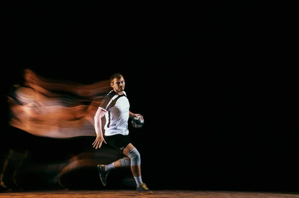 Jovem jogador de handebol contra fundo escuro estúdio em luz mista — Fotografia de Stock