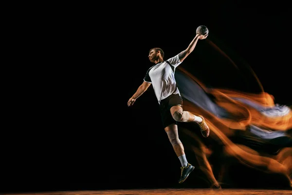 Ung handbollsspelare mot mörk Studio bakgrund i blandat ljus — Stockfoto