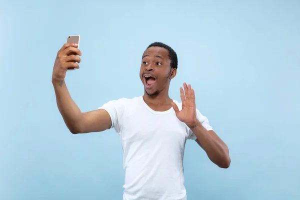 Media longitud primer plano retrato de hombre joven sobre fondo azul . — Foto de Stock