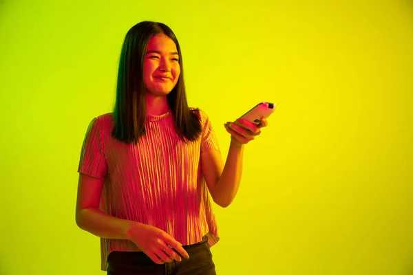 Krásný ženský výraz v neonové světelné tváři na žlutém studiovém pozadí — Stock fotografie