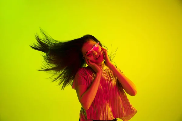 Beautiful girls facial expression in neon light on yellow studio background — Stock Photo, Image