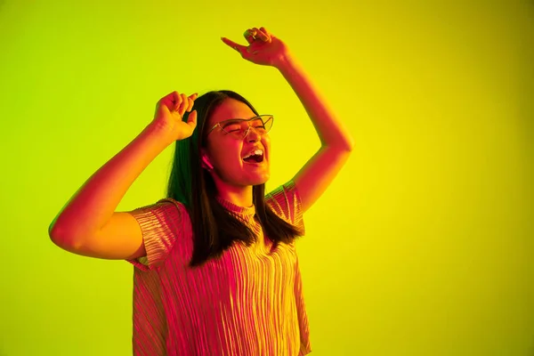Gadis cantik ekspresi wajah di lampu neon pada latar belakang studio kuning — Stok Foto