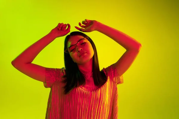Krásný ženský výraz v neonové světelné tváři na žlutém studiovém pozadí — Stock fotografie