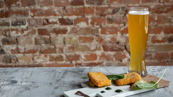 Glass of light beer on the stone table and bricks background — Stock Photo, Image