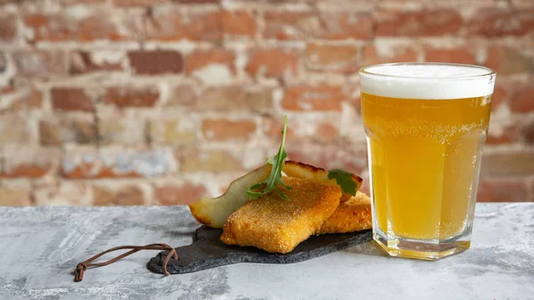 Glass of light beer on the stone table and bricks background — Stock Photo, Image