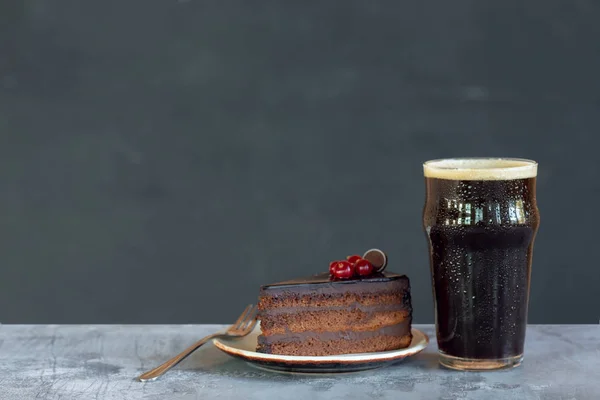 Vaso de cerveza oscura sobre la mesa de piedra y fondo gris —  Fotos de Stock