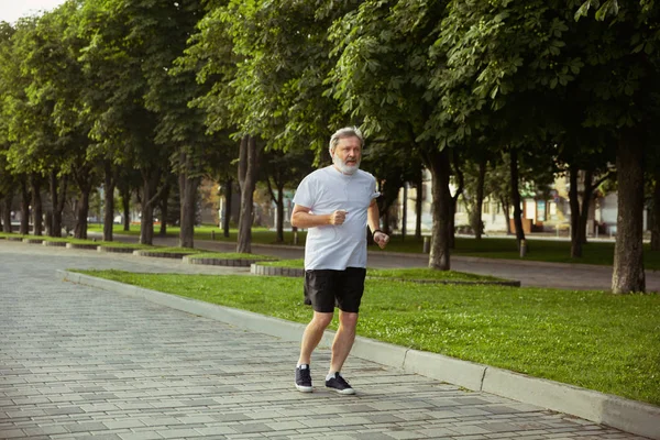 Homem sênior como corredor com braçadeira ou rastreador de fitness na rua citys — Fotografia de Stock